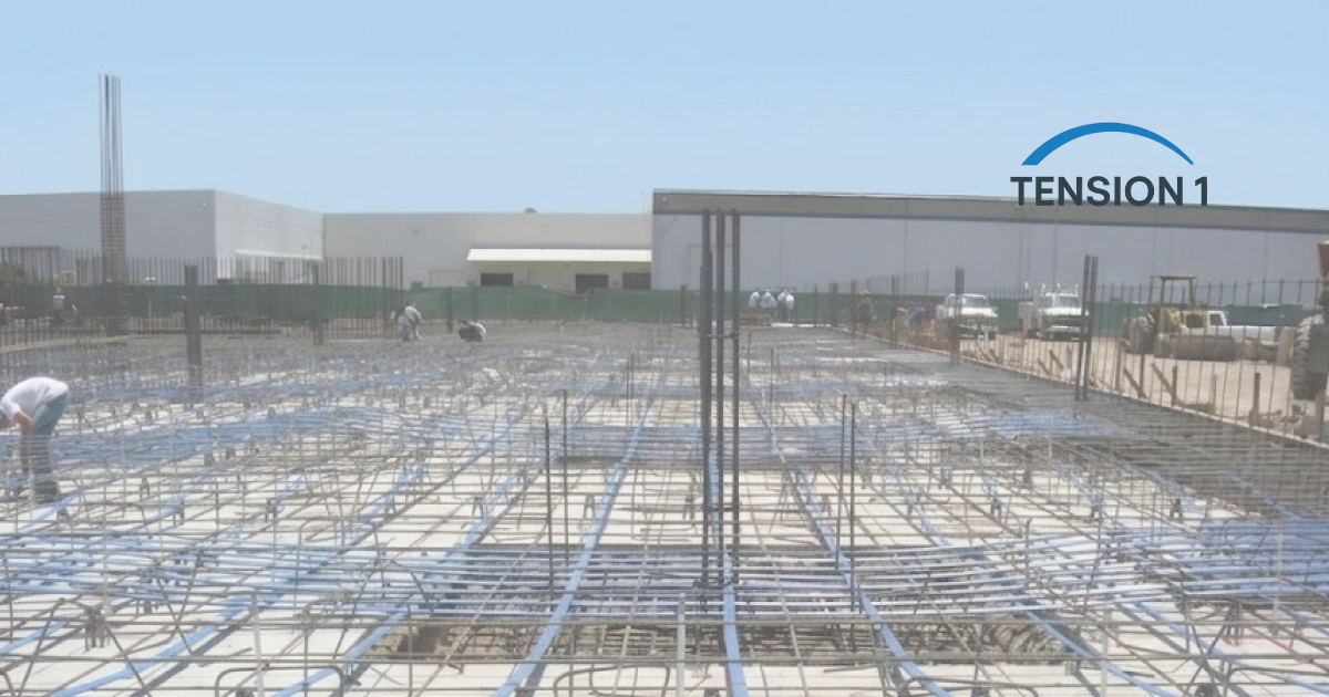 Grid layout of blue unbonded post tension slab tendons and steel rebar installation on a commercial construction site before concrete pouring.